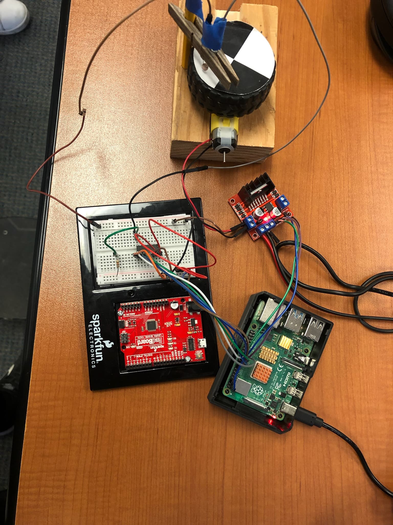 Raspberry Pi vehicle electronics, motor driver, geared motor, and optical wheel sensor assembled on a workbench